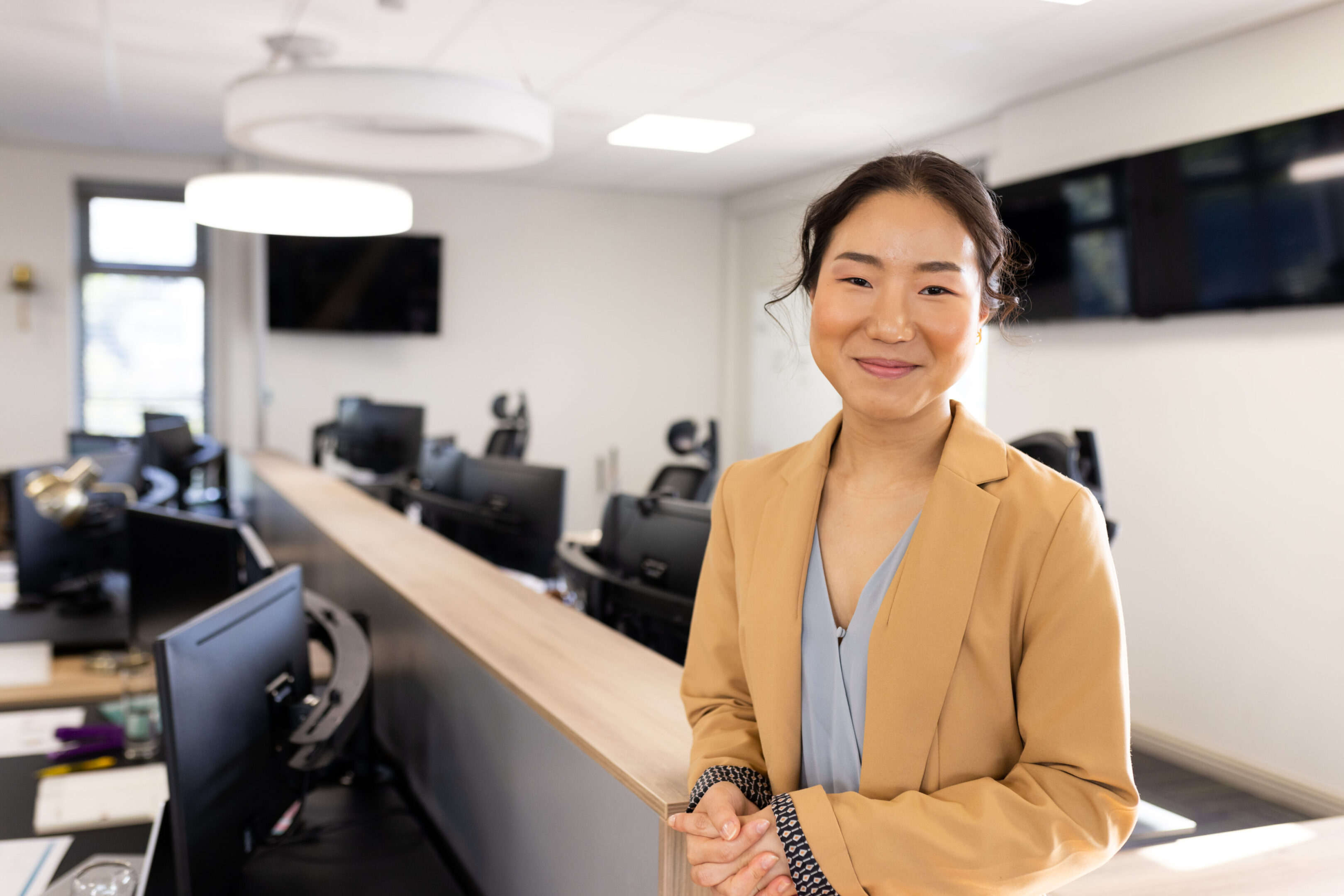 A woman standing in front of a desk with other people.