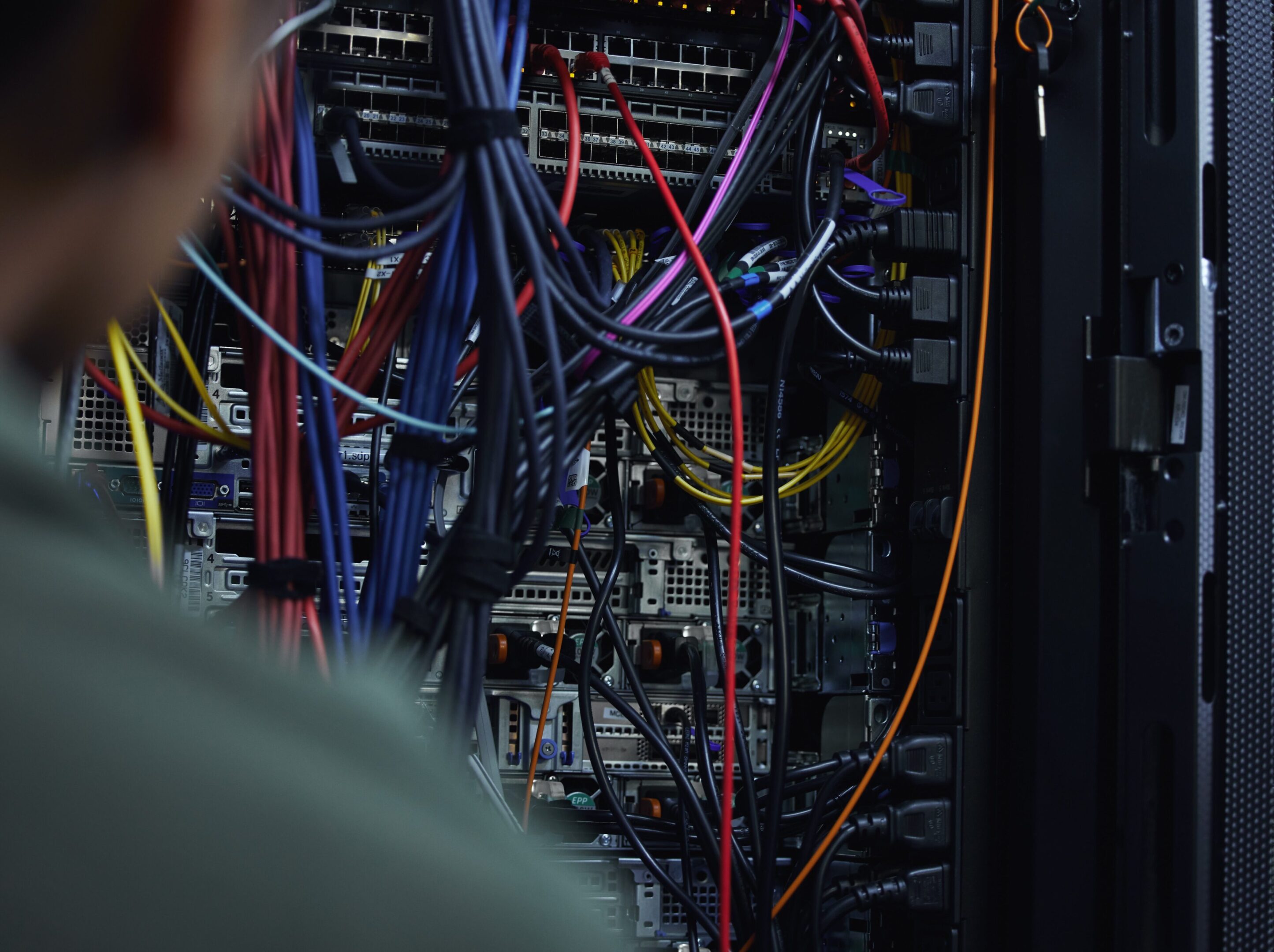 A man looking at wires in an electrical cabinet.