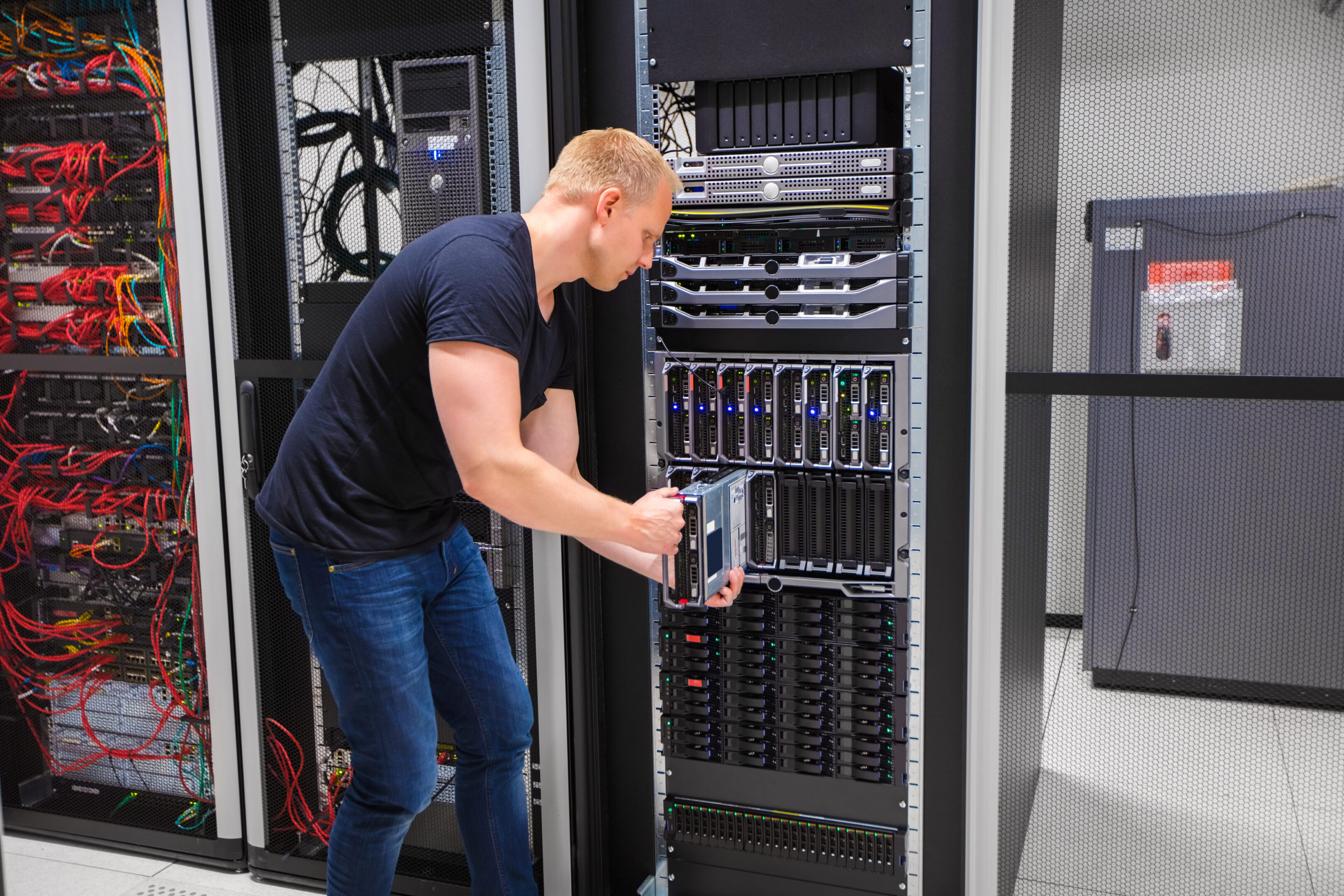 A man in black shirt standing next to server racks.